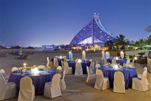 Dubai JUMEIRAH BEACH HOTELWas tun, wenn den Stararchitekten in der Stadt der Superlative die Ideen für neue spektakuläre Bauwerke ausgehen? Klar: back to basics, zurück an den Strand – aber bitte mit Luxus! Im Jumeirah Beach Hotel verlegte man eines der 19 (!) Restaurants mit schick eingedeckten Tischen und Sesseln, Silberbesteck und Fine-Dining-Menü nach draußen in den Sand – mit Blick auf den imposanten Hotelkomplex, der in seiner Form an die Spitze eines Segelmasts erinnert. Neben den Sonnenschirmen und Strandliegen zu Abend zu essen, erzeugt ein einzigartiges Flair. Und was serviert wird, begeistert ebenso: mediterrane Küche vom Feinsten. Wolfsbarschfilet in Kräuterkruste etwa, oder eine Meeresfrüchte-Paella. Oder knackige King Prawns, die zugleich Signature Dish sind.&nbsp; Rechtzeitiges Reservieren ist ein Must in diesem 617-Zimmer-Tempel, und die Wasser- Erlebniswelt sollte man sich im Anschluss an das Dinner nicht entgehen lassen. www.jumeirah.com