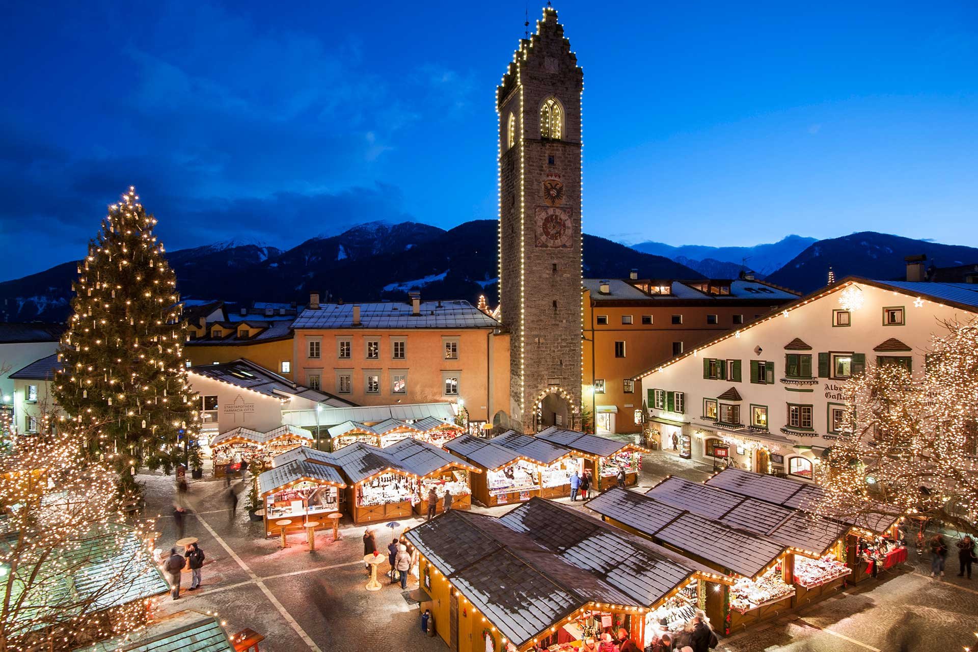 Unter dem historischen Zwölferturm in traditioneller Weihnachtsbeleuchtung erstrahlen die Marktstände des beliebten Sterzinger Christkindlmarktes.