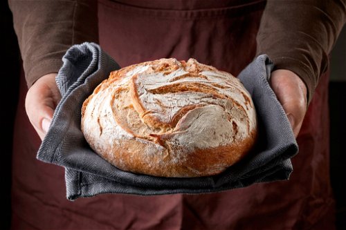 Frisch gebackenes Brot in Bäckerhänden.
