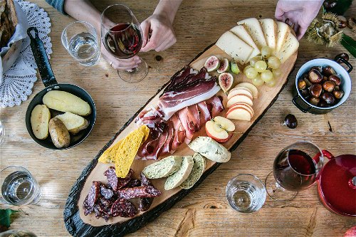 Speck, Kaminwurzen, Käse, Kastanien, Wein und die letzten Früchte der Saison: Der Tisch ist reich gedeckt.
