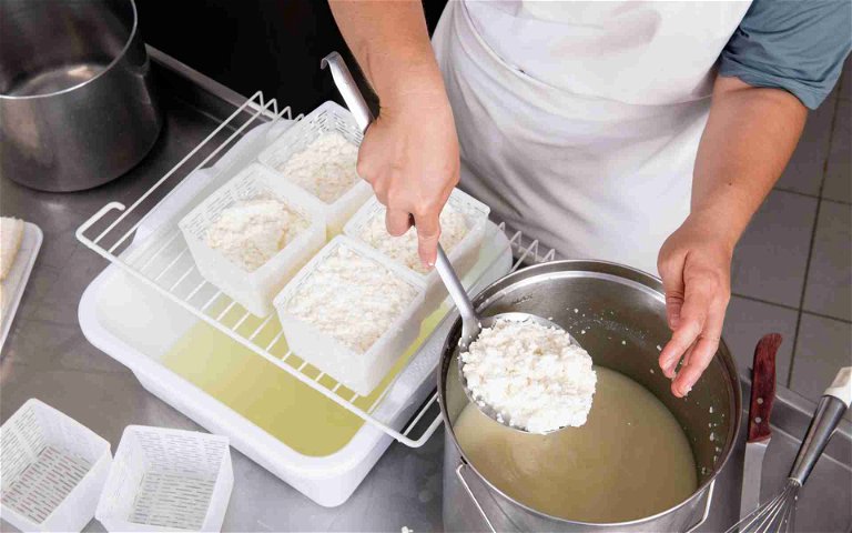 Cheesemaking: ladling curds into cheese moulds