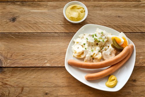 Der berühmte Kartoffelsalat mit Würstchen zählt – neben weiteren Klassikern wie Fondue und Raclette – zu den deutschen Essenstraditionen am Silvesterabend.