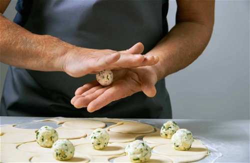 Form small dumplings from the filling and place them in the centre of the dough circles.