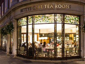 St HELENS SQUARE, YORK, UK - SEPTEMBER 9, 2016. The exterior and window of the popular Betty's Cafe and Tea Rooms in York, UK at night with a warmly lit interior.
