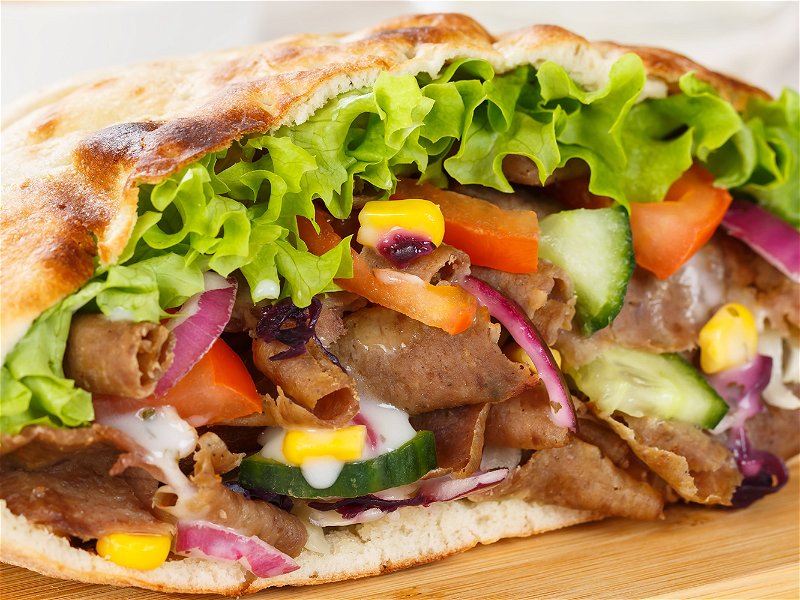 Döner Kebab Doner Kebap slice fast food in flatbread with French Fries on a wooden board sliced