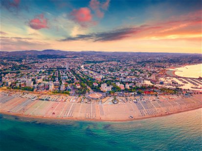 Panoramic summer view from flying drone of Libera Rimini public beach. Amazing evening scene of Italy, Europe. Stunning sunset on Adriatic coast. Vacation concept background.
