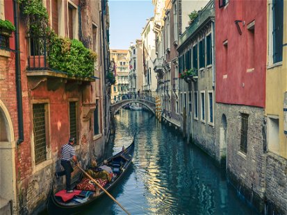 Classical picture of the venetian canals with gondola across the canal.