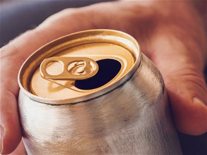 Man drinking a cold beer after work in the evening. Hand holding a aluminum can.