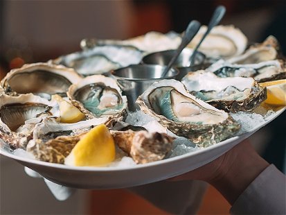 a waiter holds a serving of oysters in a restaurant