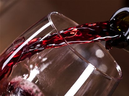 Bottle filling the glass of wine on wooden background
