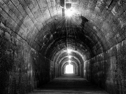 Historic bunker tunnel from world war 2 built with reinforced concrete now is a scary lost place in the dark with stalactites, old light bulbs, wet walls and a spooky atmosphere black and white vintag