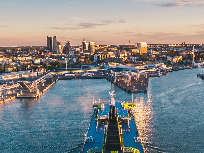 Aerial drone view of the huge cruise ferry arriving to the port of Tallinn at sunset with a Tallinn cityscape view on the background