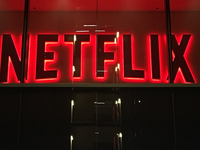 LOS ANGELES, CA, AUG 2018: entrance to streaming video-on-demand company, Netflix offices in Hollywood at night, with giant video screens partially visible in lobby, focus on corporate logo above door