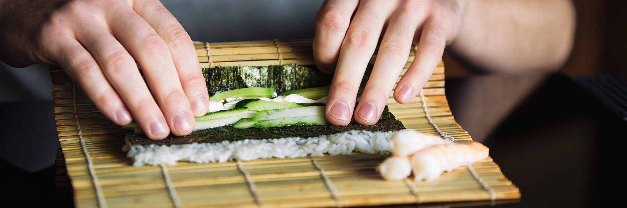 Rolling up sushi on a bamboo mat.