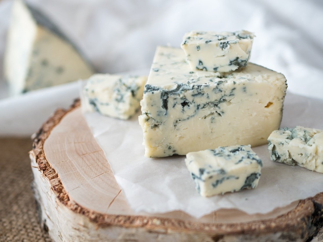 Tasty blue cheese on a wooden background and burlap. Dorblu cheese pieces