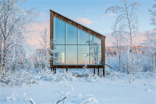 Durch die raumhohen Fenster der stylischen Holzhäuschen zeigt sich die skandinavische Winterlandschaft von ihrer schönsten Seite.