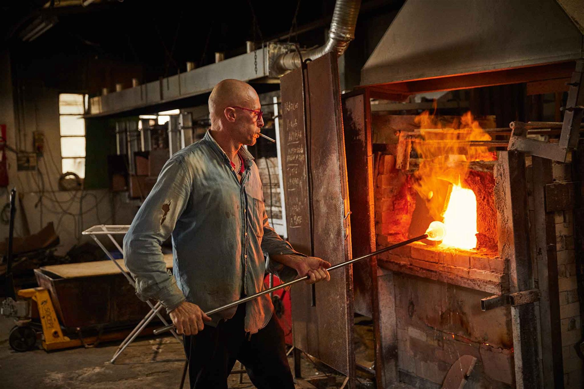 Das Glasstück wird an langen Metallstücken in den Brennöfen bis zu über 1000 Grad Celsius erhitzt und mit Werkzeugen geformt.