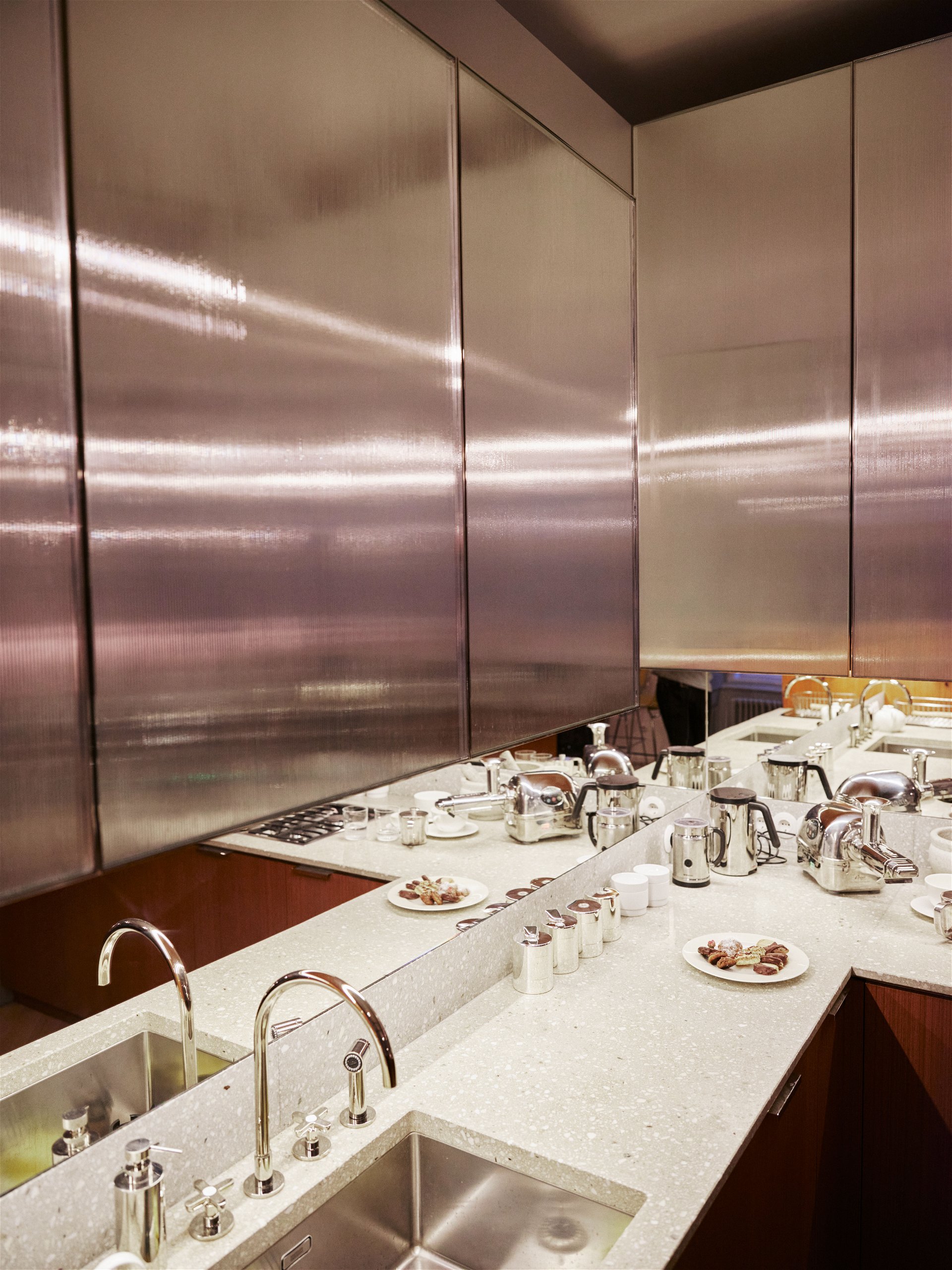 Wohnküche: Materialien und Design in der Küche verschmelzen mit dem restlichen Wohnraum. Die doppelt verglasten Oberschränke haben einen seidigen Schimmer und reflektieren das Licht.