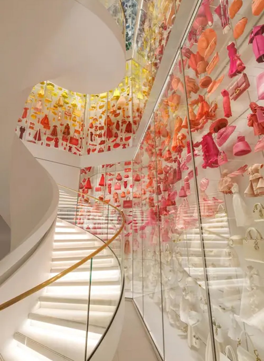 An den Wänden neben der großzügigen, sich frei durch den Raum windenden weißen Treppe ist hinter Glas eine außergewöhnliche Sammlung von fast 1.500 Miniaturobjekten aus dem Dior-Universum zu bewundern, die im 3D-Druckverfahren hergestellt wurden.