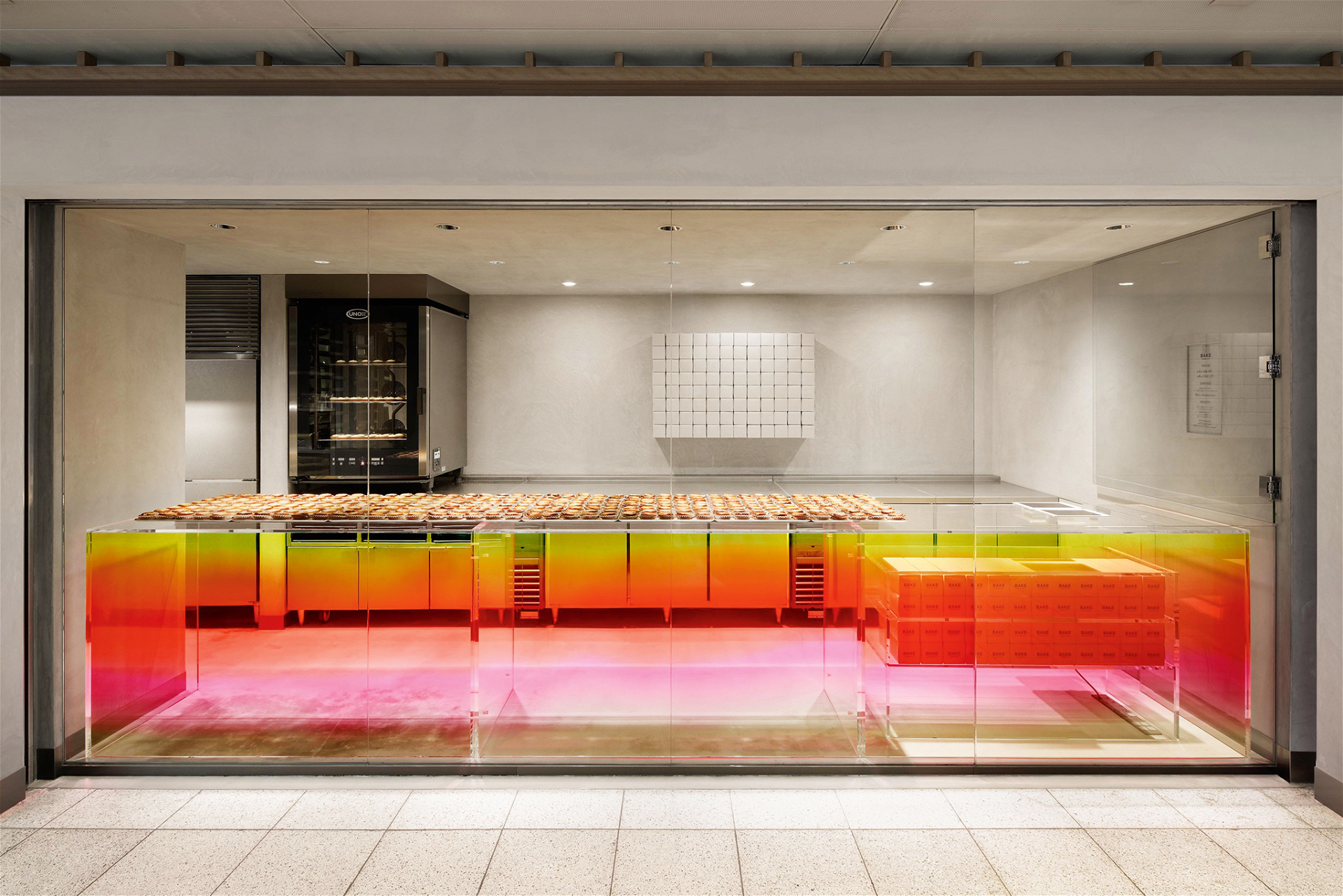 Bake Kitasenju, Tokio In dieser Filiale gestaltete der japanische Designer Yota Kakuda die zentrale Theke aus Acrylglas in strahlendem Pink, Gelb und Orange und setzte graue Aluminumfliesen in den Innenbereich. cheesetart.com
